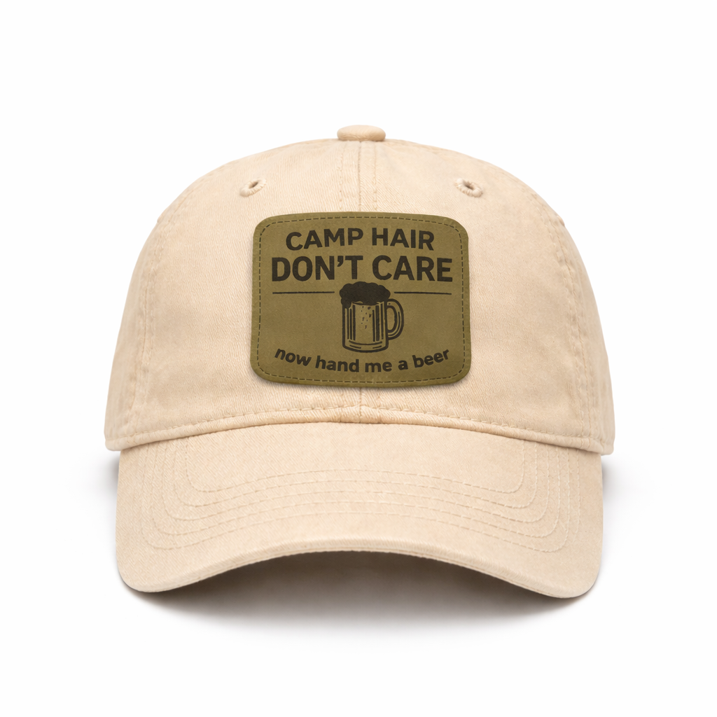 Beige cap with a patch that says 'Camp Hair Don't Care, now hand me a beer' on a white background