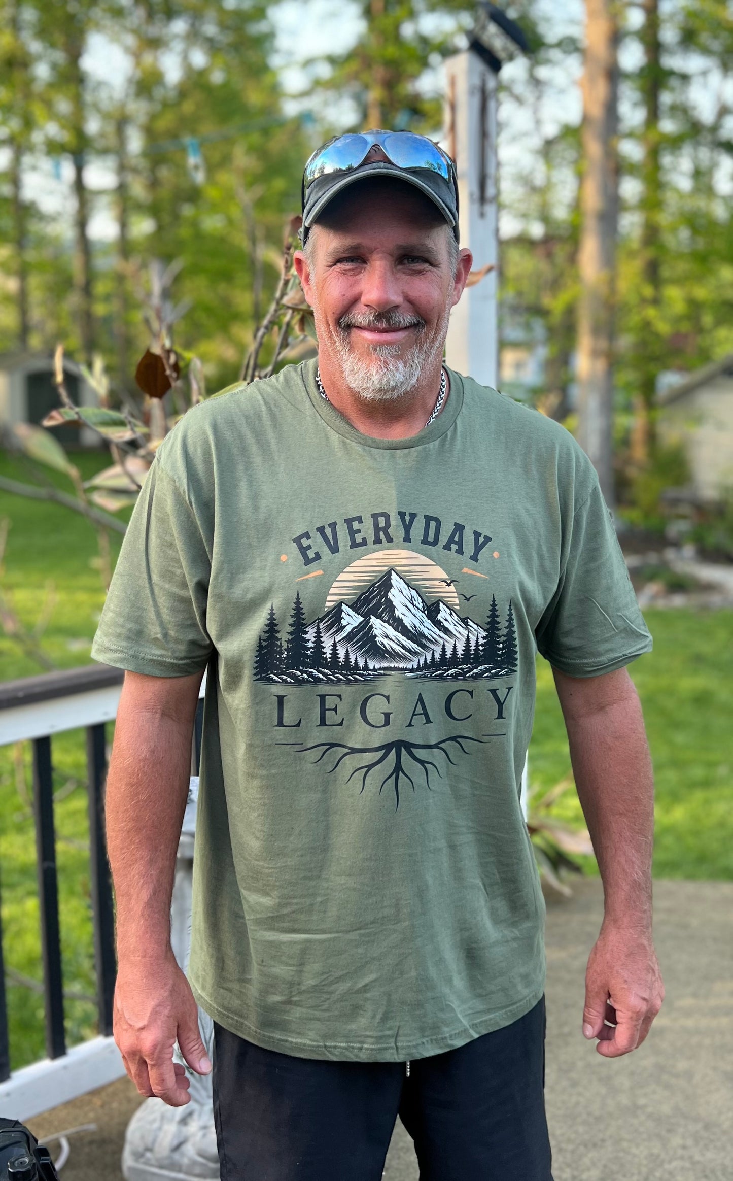 Man wearing a green t-shirt with 'Everyday Legacy' design outdoors.