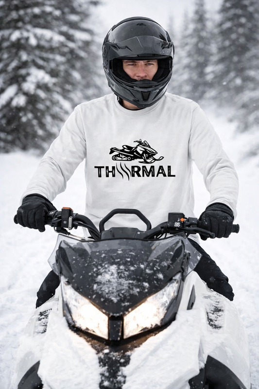 Person on a snowmobile wearing a white jacket with 'THRMAL' branding in a snowy forest setting