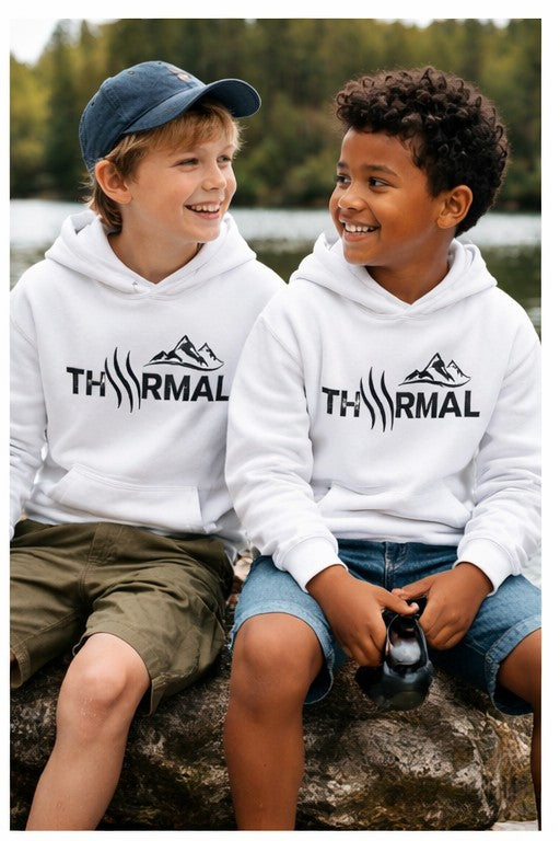 Two children wearing white hoodies with 'Thermal' logo sitting by a lake.