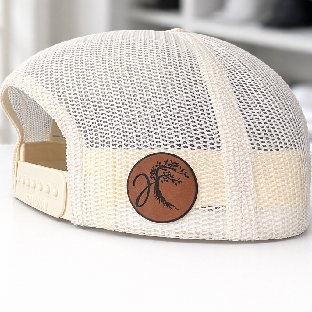 White mesh cap with a brown leather patch on a white surface
